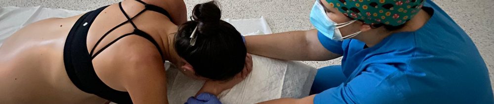 grávida em trabalho de parto debruçada na bola de pilates e sendo apoiada por médica obstetra
