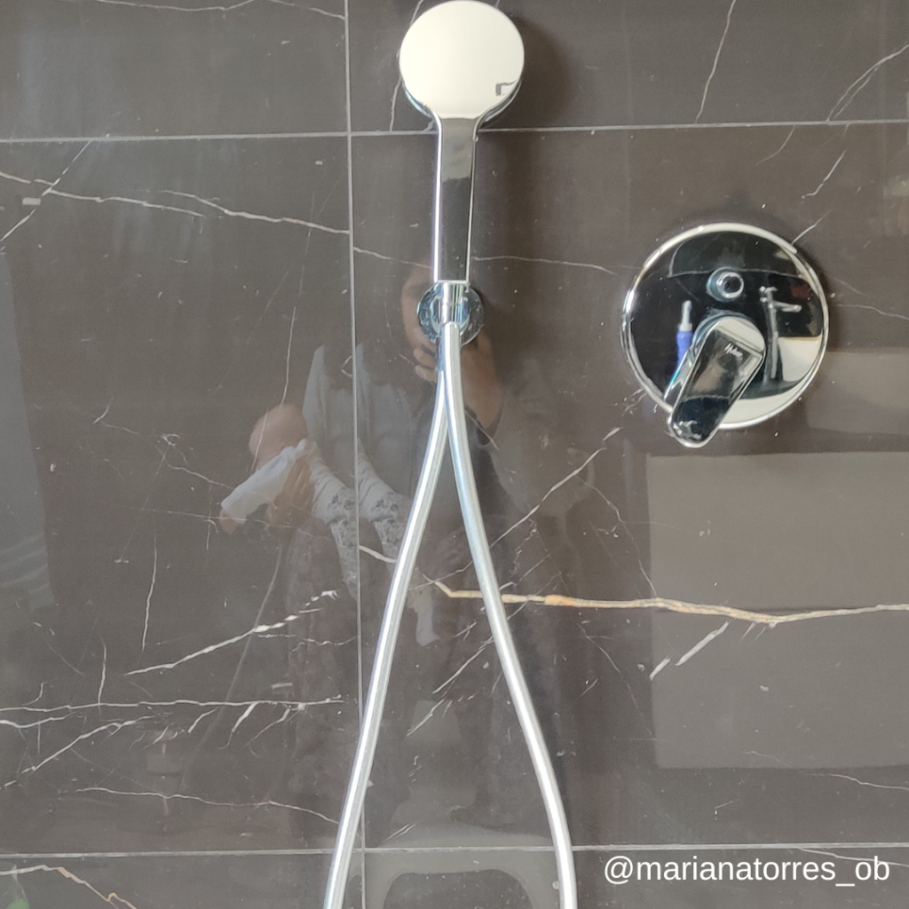 puérpera no wc com bebe ao colo refletida no azulejo